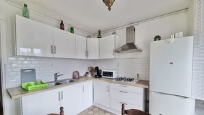 A kitchen with white cabinets, a microwave, a gas stove, and a refrigerator. - #CX |Chez Faffa 𓅂| Spacious T5 | Train station | (Grenoble)