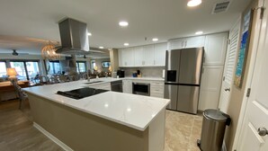 A modern kitchen with a large island, stainless steel appliances, and a view to the outside.