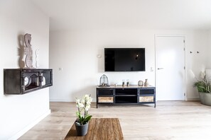 Relax in this stylish living room with a flat-screen TV, coffee table, and lush greenery.