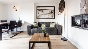Una sala de estar moderna con una mesa de centro de madera, sofá gris y una fotografía enmarcada de una playa en la pared.