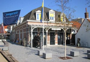 A building with a traditional facade, a flagpole with a flag, and a cobblestone street.