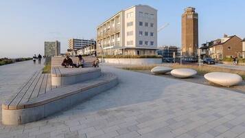 A public square with a modern building, a tall tower, and a paved area with benches.