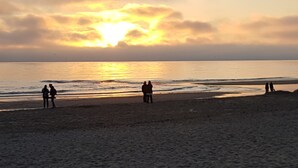 Una spiaggia con persone che camminano lungo la riva al tramonto.