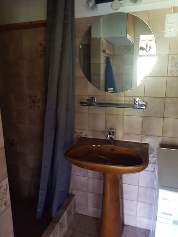 A bathroom with a brown sink, a mirror, and a shower area. - Large vacation home right across from the dunes (Julianadorp aan Zee)