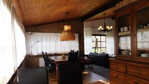 Zona pranzo con tavolo in legno, sedie e lampadario. C'è anche un divano e un mobile vetrina.