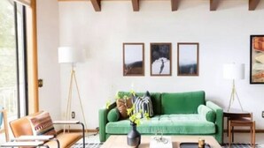 A living room with a green sofa, a coffee table with a vase, and framed pictures on the wall. - Lakeshore Villa (Incline Village)