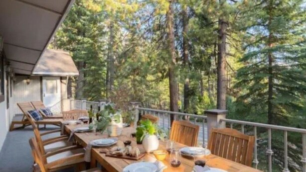 An outdoor dining area with a wooden table set for four, surrounded by chairs. - Lakeshore Villa (Incline Village)