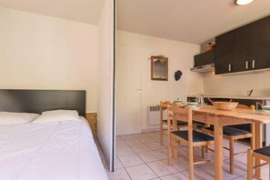 A bedroom with a bed and a small kitchenette with a table and chairs. - 200m from resort center, 3rd floor, balcony, tv, 30m², Serre Chevalier (Briançon)