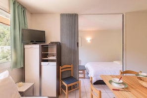 A hotel room with a bed, a desk with a chair, a television, a wardrobe, and a window with curtains. - 200m from resort center, 3rd floor, balcony, tv, 30m², Serre Chevalier (Briancon)