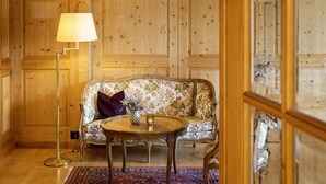 Une pièce aux murs lambrés, avec un canapé à motifs floraux, une table ronde en bois et un lampadaire.