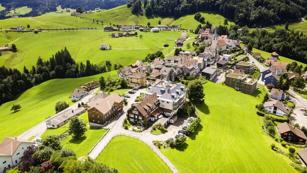 Une vue aérienne d’un village avec des maisons, des routes et des champs verdoyants.