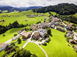 Vista aérea de un pueblo con casas, caminos y campos verdes.