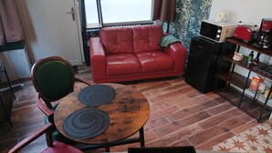 A compact living space with a red leather sofa, a small wooden dining table with two placemats, a kitchen area with a refrigerator, a toaster, and a coffee maker. - L'Étoile - studio in the heart of Chinon (Chinon)
