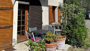 Ein zweigeschossiges Gebäude mit einer Stein-Fassade, Holzläden und einem Balkon mit Metallgeländern.