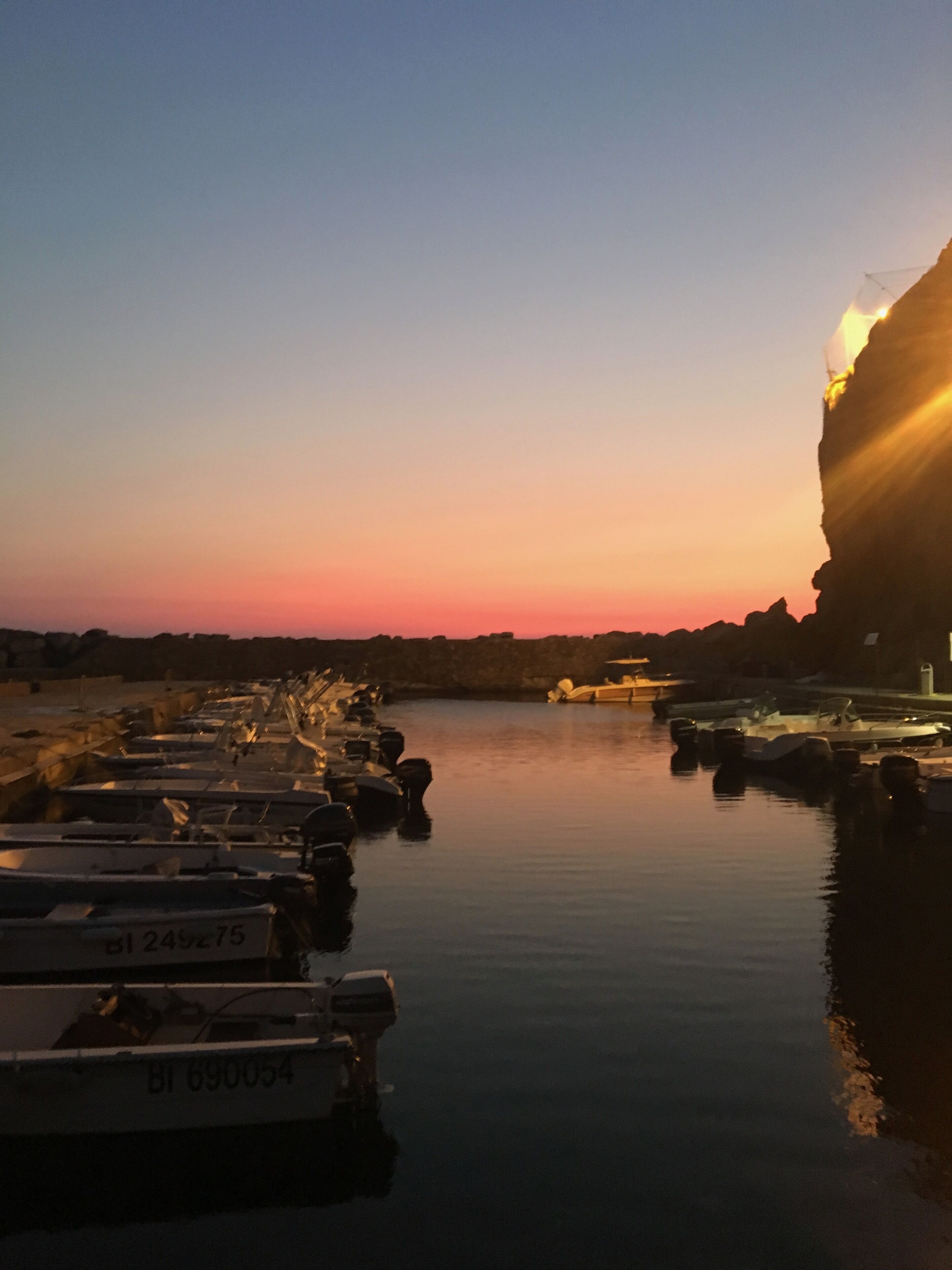 Un port de plaisance au coucher du soleil, avec des bateaux amarrés.