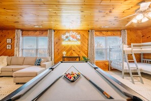 Relax in this inviting room at Gymlady Oak Lodge, featuring a pool table, sofa, and bunk bed for multiple guests.
