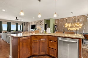 A modern kitchen with a central island, wooden cabinets, and a stainless steel dishwasher.