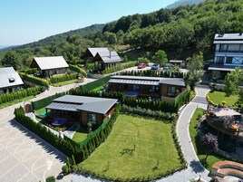 Un resort moderno con varias construcciones, céspedes bien cuidados y una vista despejada de las colinas boscosas circundantes.
