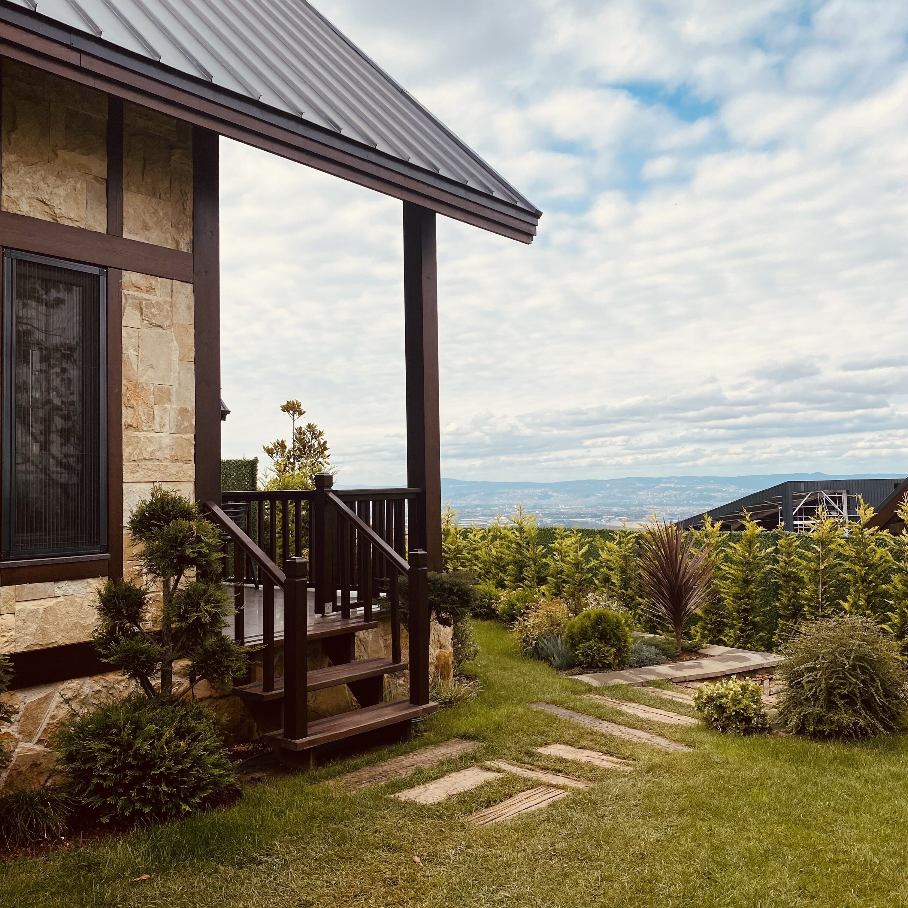 Una casa con facciata in pietra, un portico in legno e vista sulle montagne lontane.