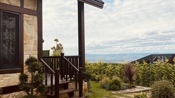 Una casa con facciata in pietra, un portico in legno e vista sulle montagne lontane.