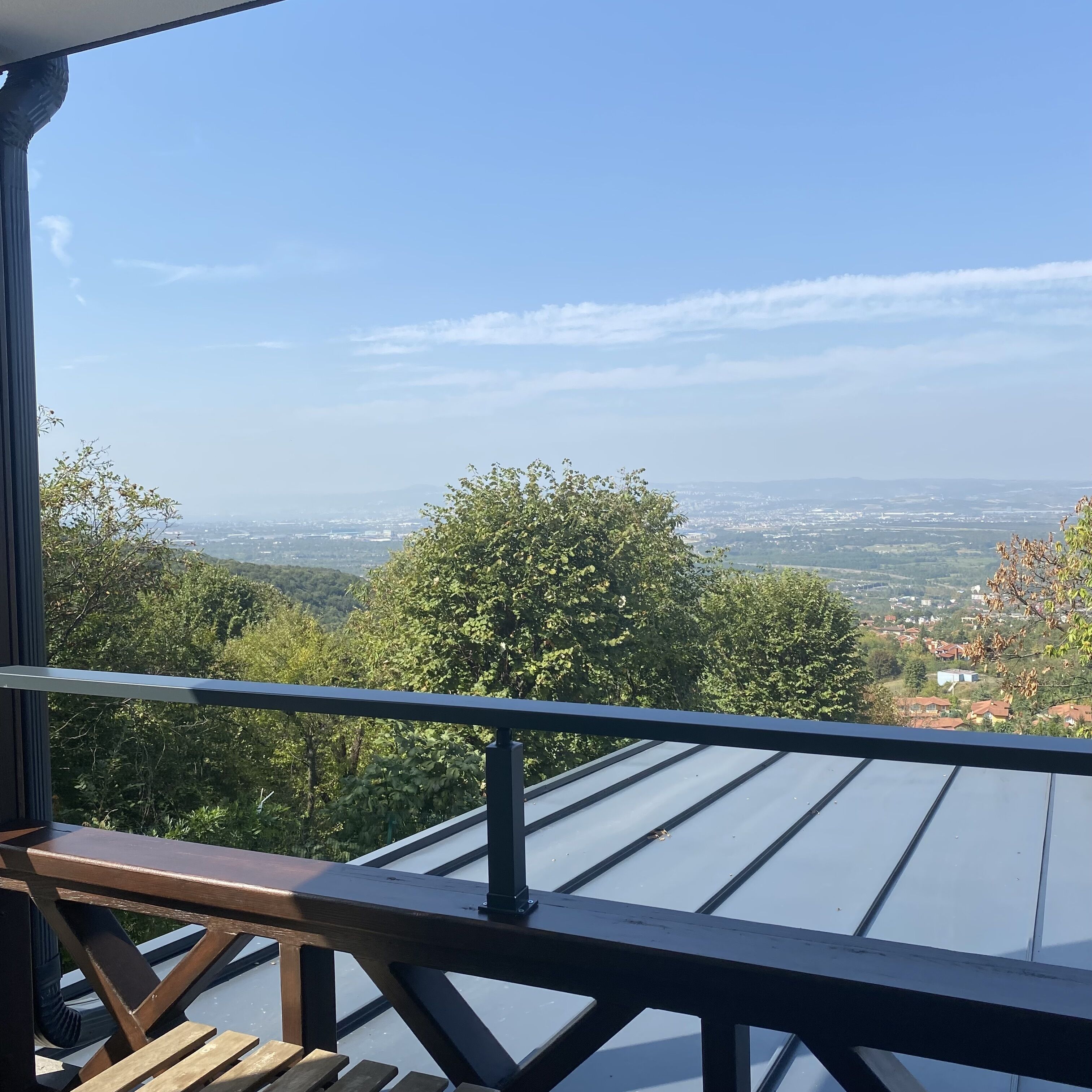 Un balcón con vistas a un paisaje urbano y áreas verdes.