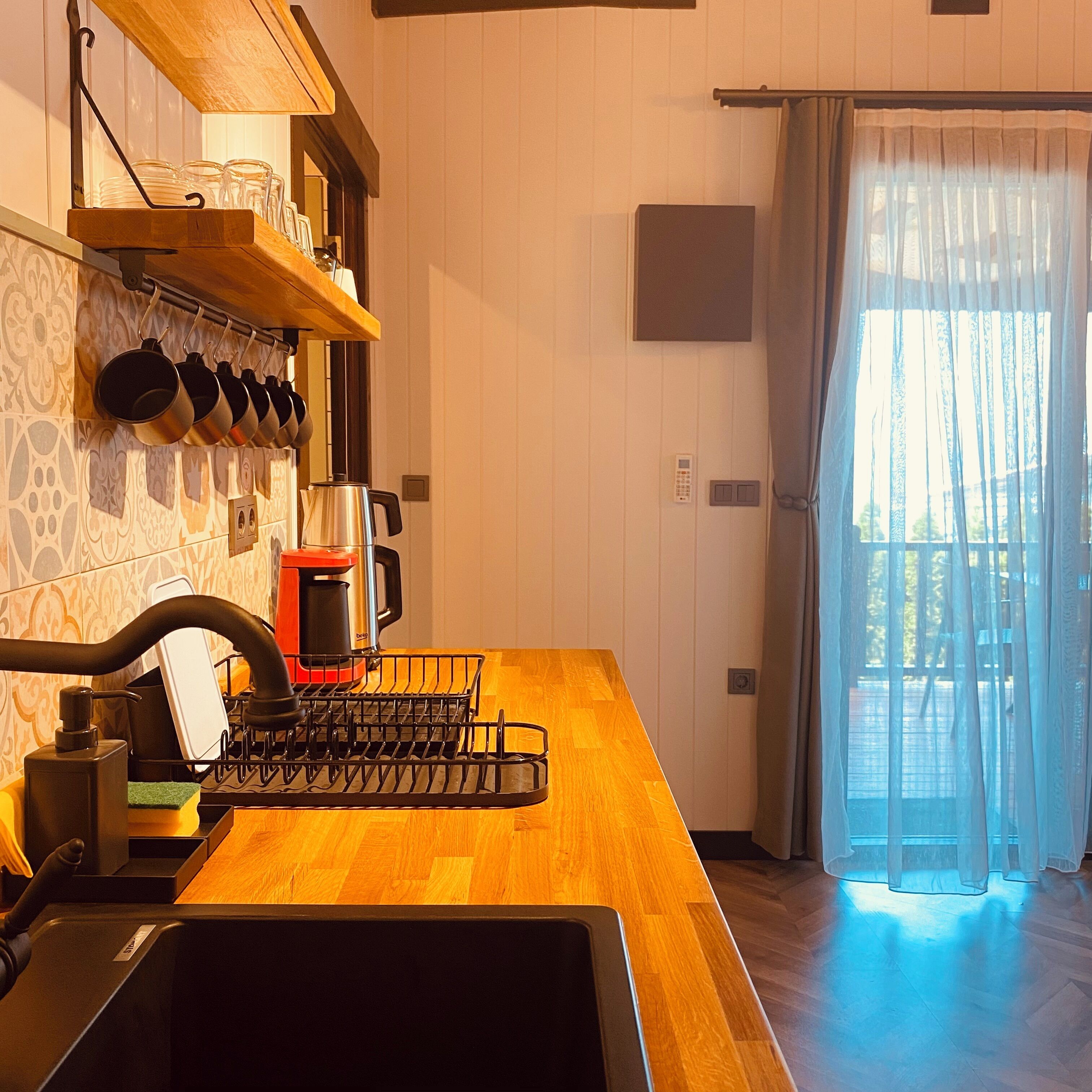 A kitchen with a wooden countertop, a coffee maker, and a dish rack.
