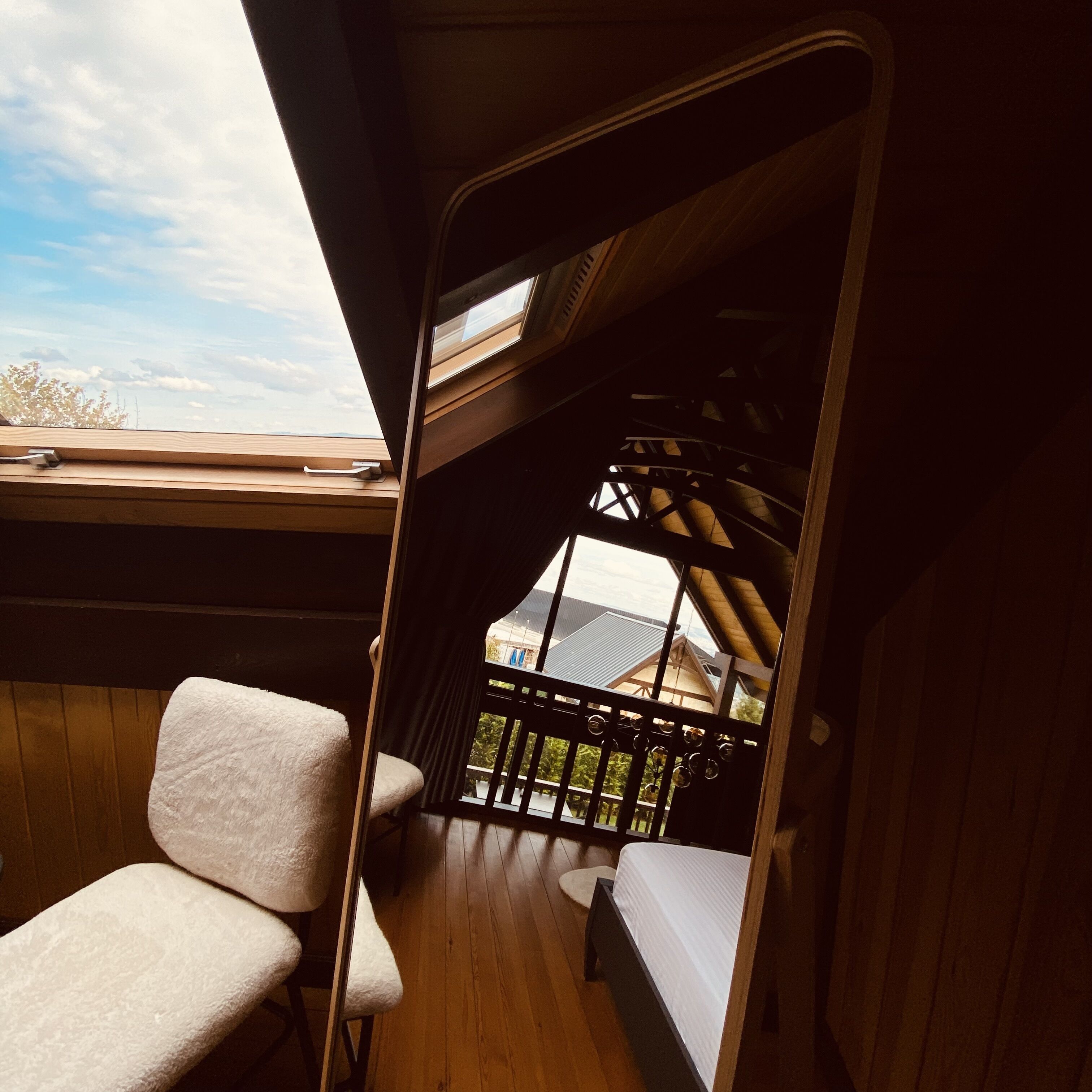 Una habitación con piso de madera, una cama, un ventanal y vista a un edificio.