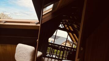 Una habitación con piso de madera, una cama, un ventanal y vista a un edificio.