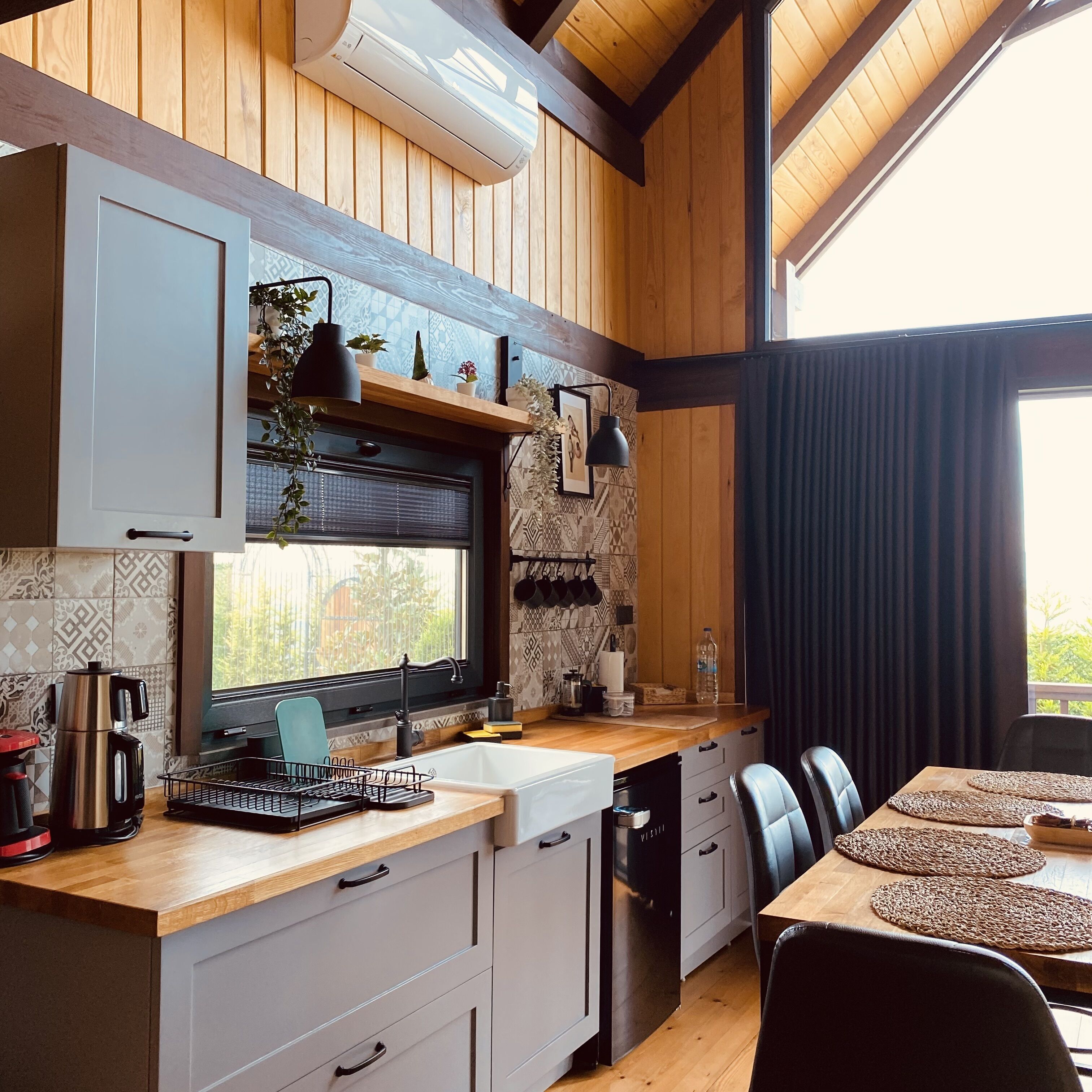 Una cocina moderna con armarios de madera, una estufa integrada y un ventanal con vistas al jardín.