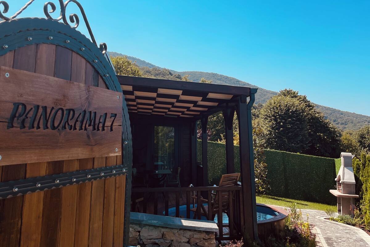 Un panneau en bois portant l’inscription « PANORAMA 17 » et une pergola avec des sièges à l’extérieur.