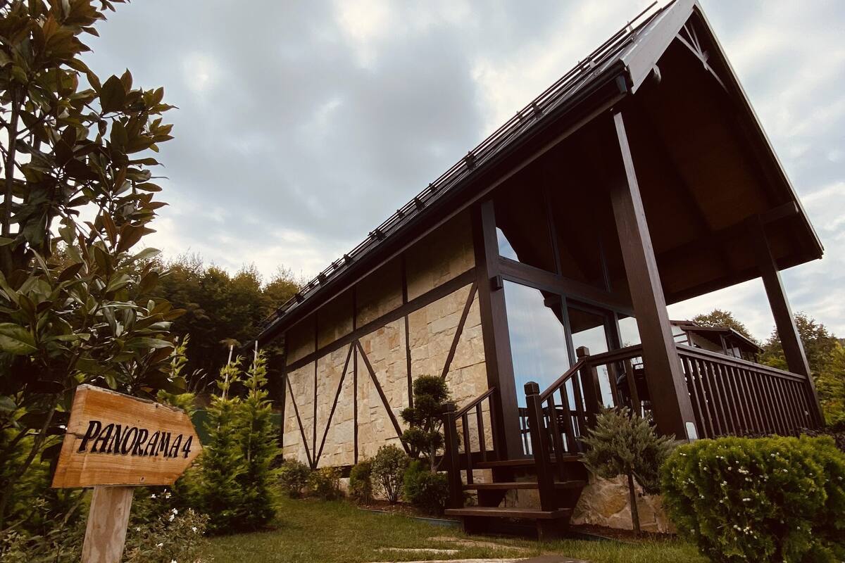 Un bâtiment doté d’une façade en pierre, d’une terrasse en bois et d’une enseigne indiquant « PANORAMA 4 ».