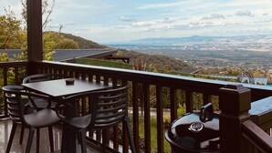 Een balkon met een tafel en stoelen, met uitzicht op een landelijk panorama en een verre skyline.