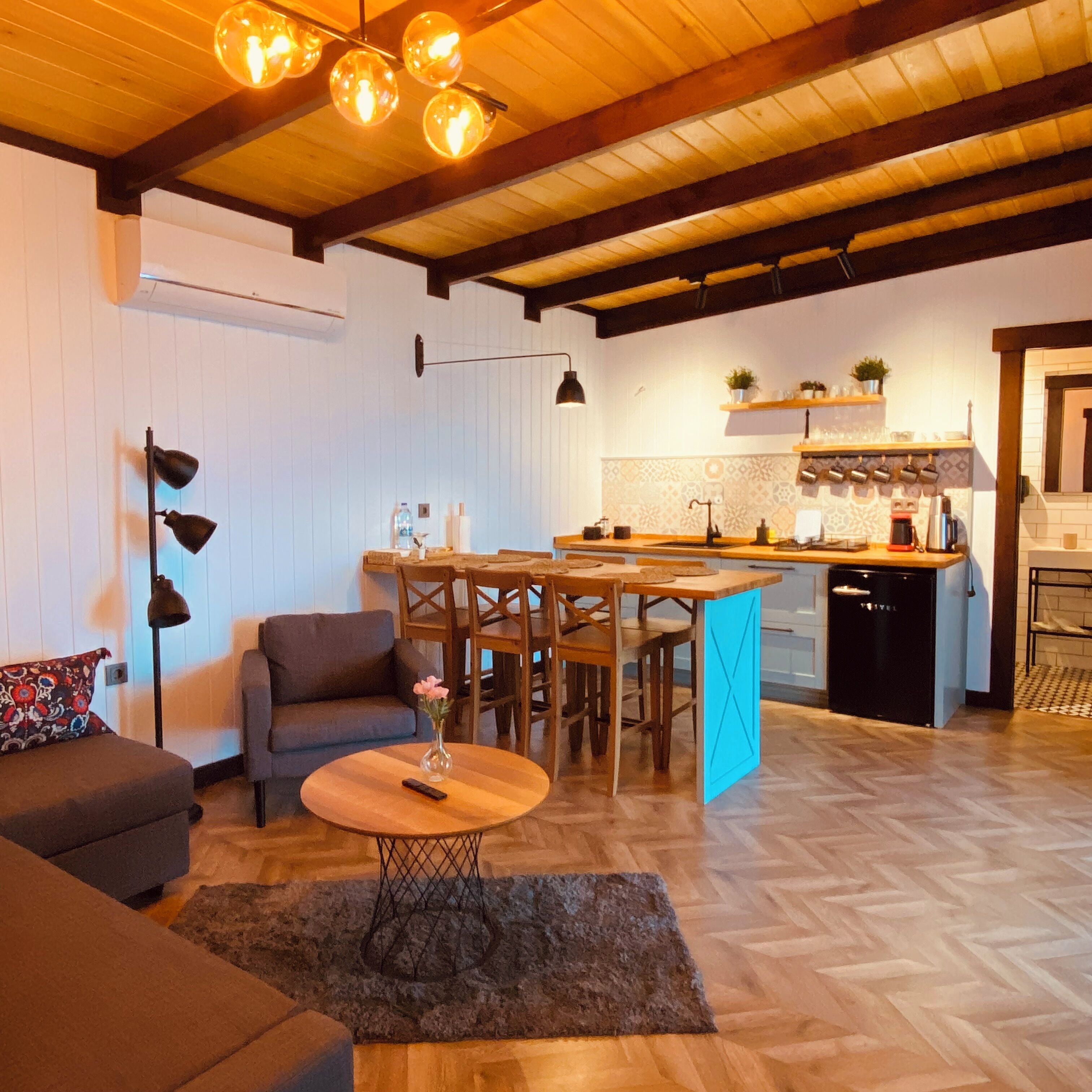 A cozy living room with a sofa, a coffee table, and a dining area with a kitchen in the background.