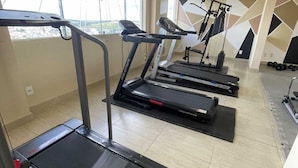 Ein Fitnessraum mit Laufbändern, einer Hantelbank und einem an der Wand befestigten Trainingsgerät.