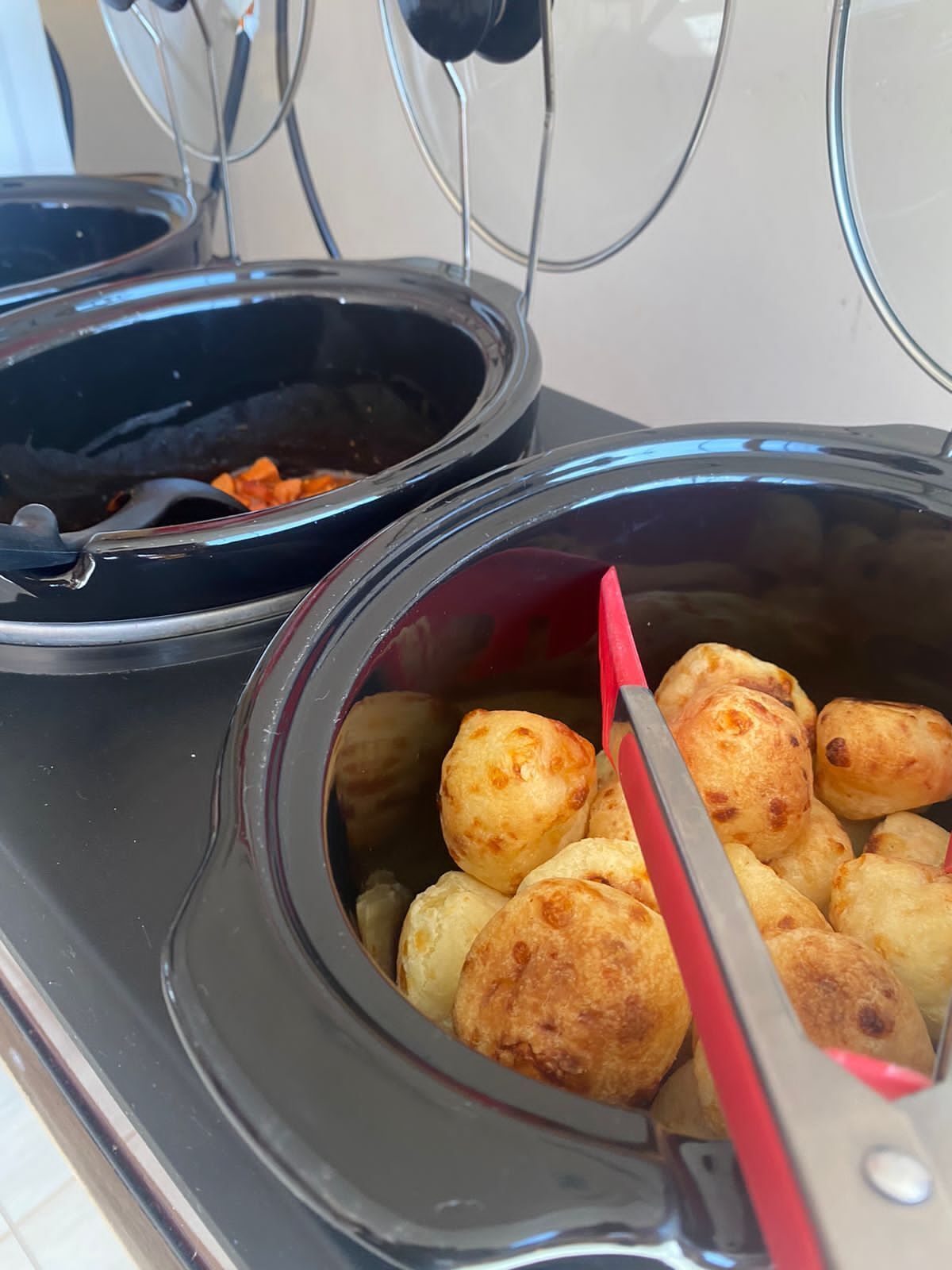 Disposição de buffet com duas tigelas, uma com doces dourados e a outra com molho escuro e pedaços de laranja.