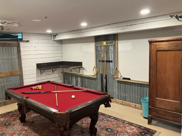 Une table de billard avec des billes, un banc et une porte.