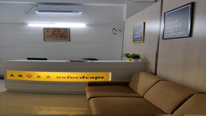 A reception area with a reception desk, a couch, and framed motivational quotes on the wall. - Abuzz Oxfordcaps Dehradun - Campus Accommodation (Dehradun)