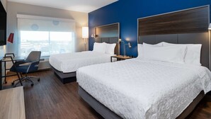 Ein Hotelzimmer mit zwei Betten, einem Schreibtisch und einem Stuhl.
