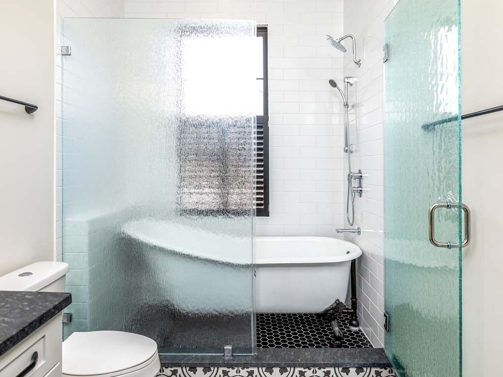 A bathroom with a glass-enclosed shower, a white bathtub, and a toilet.