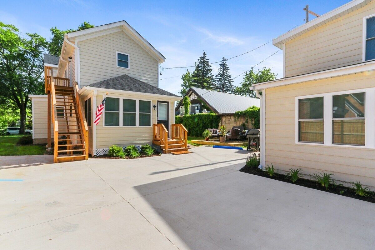 Ein Wohnhaus mit überdachter Terrasse, einer Holztreppe und einer kleinen Sitzgelegenheit im Freien.