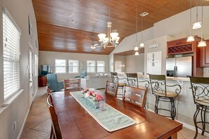 Un comedor amplio con una mesa y sillas de madera, un tapete decorativo e iluminación colgante.