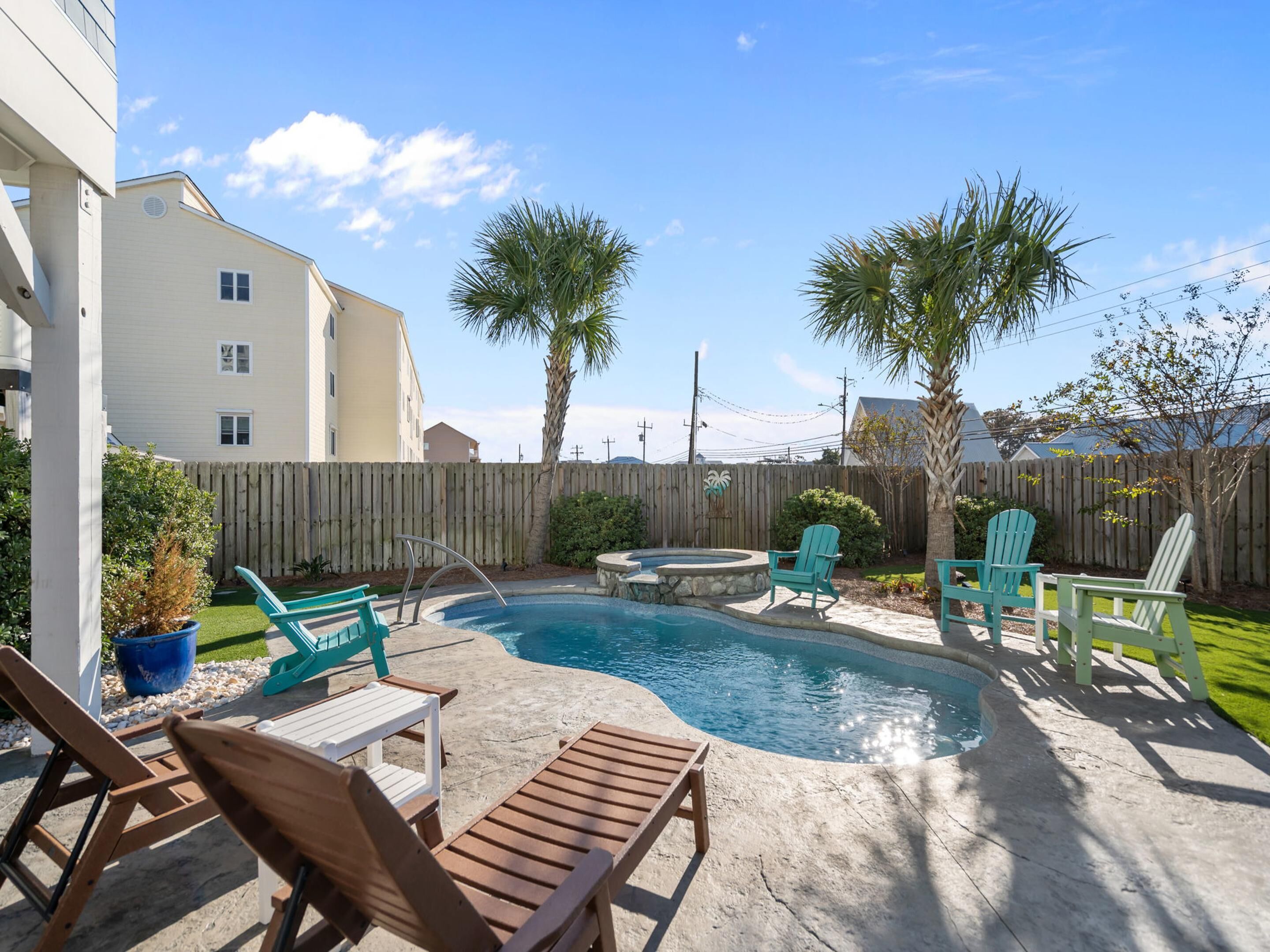 A backyard with a swimming pool, wooden deck, and outdoor furniture.
