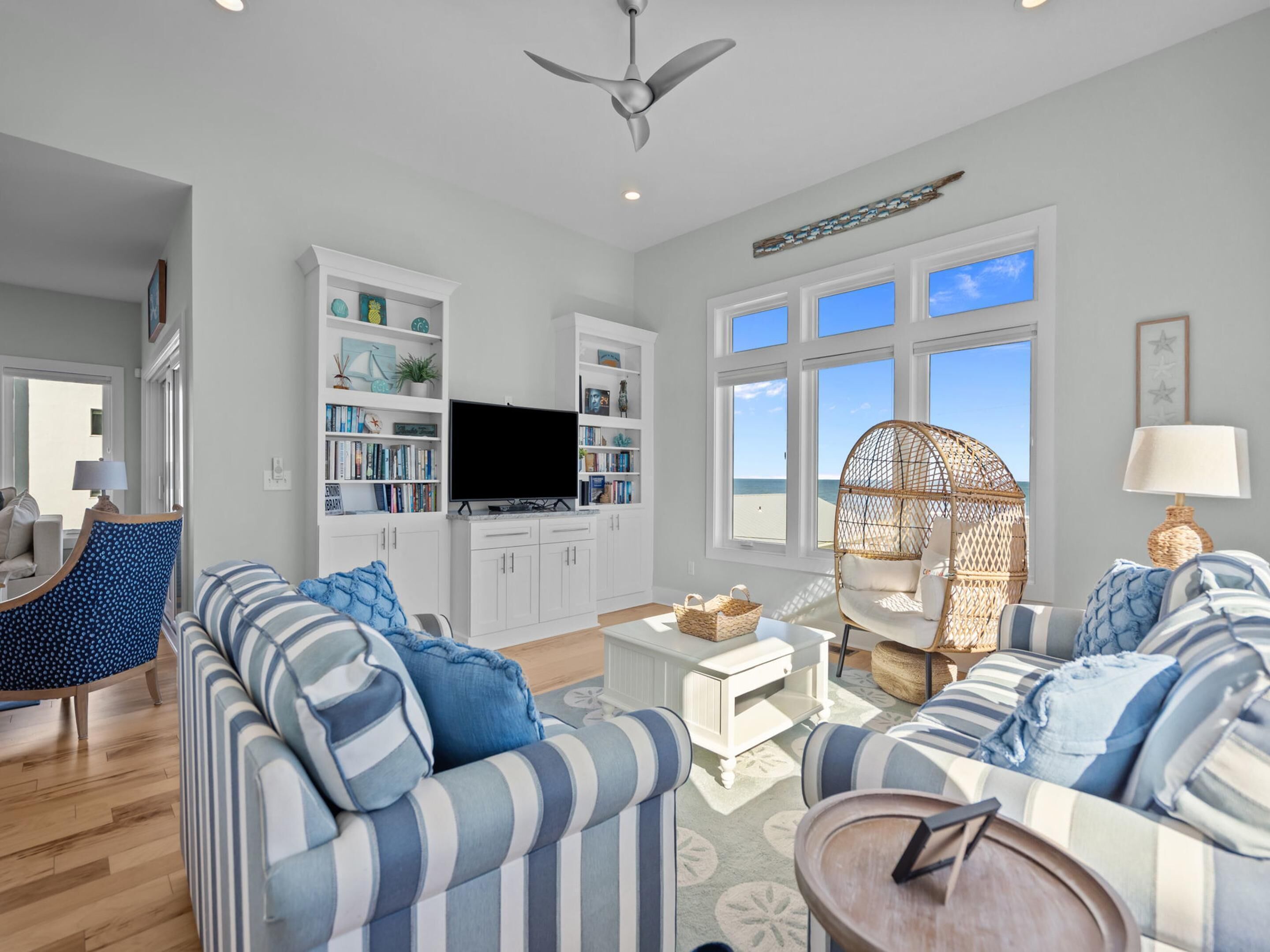 A spacious living room with a large sofa, a television, and a bookshelf.