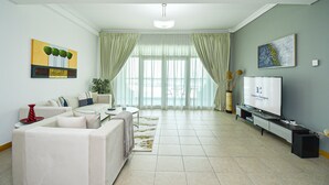 A modern living room with a sofa, TV, and curtains. - Palm Jumeirah's Spectacular Ocean-View Apartment - NBT (Dubai)