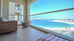A balcony with a view of a beach and ocean. - Palm Jumeirah's Spectacular Ocean-View Apartment - NBT (Dubai)