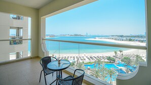 A balcony with a view of a beach and a pool. - Palm Jumeirah's Spectacular Ocean-View Apartment - NBT (Dubai)