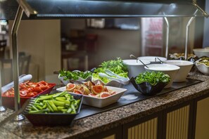 Un bufé con diversas opciones de comida, incluyendo verduras, frutas y ensaladas.