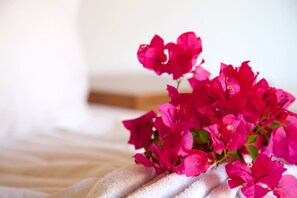 Una cama con una manta blanca y un ramo de flores rosas.