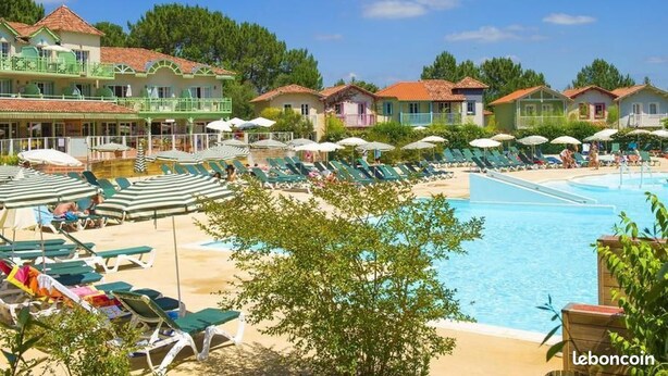 A resort with a swimming pool, sun loungers, and beach umbrellas.