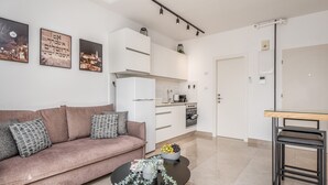En moderne stue med en sofa, et sofabord og et køkken i baggrunden.